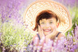 Portrait of happy cute little girl with haircut in big summer hat in lavender field with purple flowers around in sunny summer day. Summer in Provence. Travel. Child in lavender. Happiness and relax
