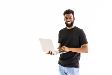 Young smiling african man standing and using laptop computer isolated over white background