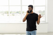 © F8  \ Suport Ukraine - Attractive smiling young african man using mobile phone while standing at the window