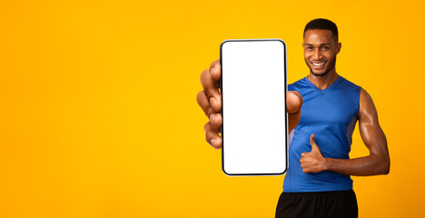 I recommend sports app. Muscular african american man holding smartphone with empty screen for mockup