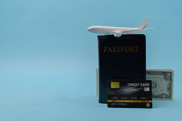 Passport, credit card, airplane, and 2 dollar bills isolated on blue background with copy space