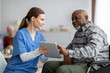 © Prostock-studio - Friendly nurse helping black senior man using digital tablet