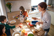 © Halfpoint - Mother of three little children preparing breakfast in kitchen at home.
