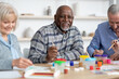 © Prostock-studio - Happy senior black man enjoying painting activity with his friends