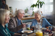 © Halfpoint - Group of cheerful seniors enjoying breakfast in nursing home care center.