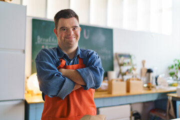 Wall Mural - Cheerful young Down Syndrome waiter working in take away restaurant, social inclusion concept.