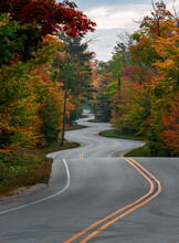 Bumpy Curvy Road Through An Autumn Forest In Door County, Wisconsin, The USA At Sunset Or Sunrise