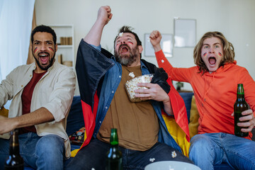 Wall Mural - Happy German football fans friends watching football at home and celebrating