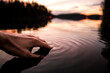 Closeup of a hand touching the water making smooth waves on the surface in a lake in sunset