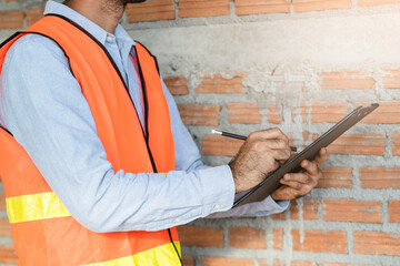 Wall Mural - Asian inspector checking structure of new property and taking note in the clipboard for review and fix the house before sell to client