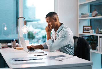 Things arent quite going his way today. Shot of a handsome young businessman working on his laptop during a late night shift at work.