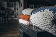Closeup shot of soft custom made chunky blankets on the wooden small table in the house