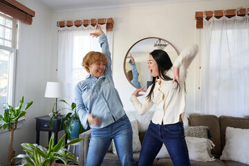 two women smile and dance in living room facing each other 