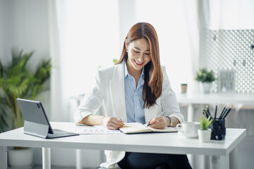 Smile Young business Asian woman freelancer is working her job on a laptop computer in a modern office. Doing accounting analysis report real estate investment data, Financial and tax systems concept.