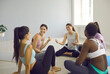 © Studio Romantic - Diverse group of happy beautiful fit young women having a nice chat after a yoga class. Cheerful multiracial female friends talking and laughing sitting in a circle on yoga mats at gym or yoga studio