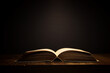 © tomertu - image of open antique book on wooden table with dark background