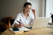 © muse studio - A freelance woman with glasses designer uses a laptop online on the website, works in a modern cozy office