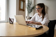 © muse studio - A woman designer with glasses designer uses a laptop online on the website, works in a modern cozy office