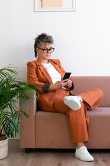 fashion business woman queer portrait, sitting on couch, using social media