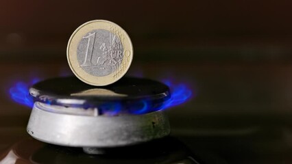 Wall Mural - gas stove burner with one euro coin standing vertically on top, burning gas