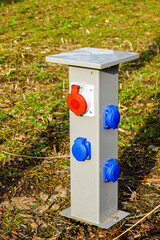 new modern multiple electrical outlets on a low metal pole in a city park