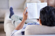 © M S/peopleimages.com - Some light reading. Rearview shot of a young man reading a novel while relaxing on the couch at home.