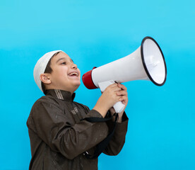 Muslim child in white traditional clothes, saying message on megaphone. High quality photo