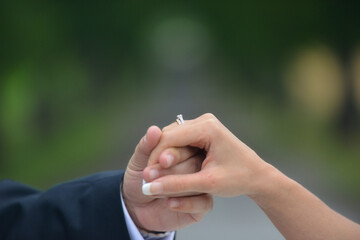 Wall Mural - Closeup of a couple holding hands at a wedding with a blurred background