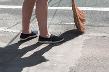 View Of Feet And Broom . Woman Sweeping The Street
