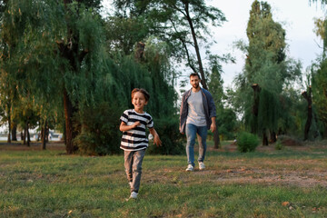 Wall Mural - Little boy with his father running in park