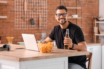 Sticker - Handsome man with laptop drinking beer in kitchen