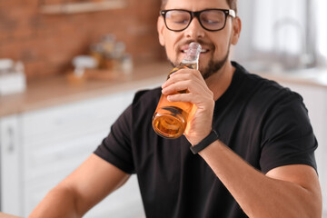 Wall Mural - Handsome man drinking beer in kitchen