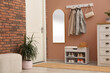 © New Africa - Rack with different shoes near pale pink wall in hall