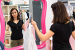 female customer in fashion outlet comparing clothing in mirror