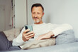 © contrastwerkstatt - older man sitting at home on sofa and looking at his cell phone