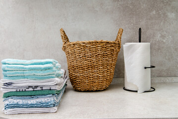 Wicker basket with clean towels and  stack of kitchen towels on the table.