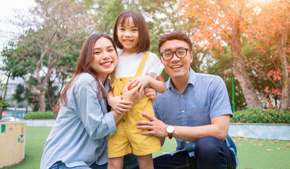 Image of young Asian family playing together at park