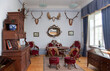 © Mint Images - Traditional furniture and hunting trophies, carved chest of drawers, wall plaques and chairs and table made from deer antlers.