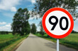 Speed limit sign with trees behind. Maximum ninety kilometers per hour. Safety on road background. White round sign red border line. Traffic ticket background. Speeding fine.