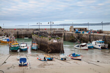 Low Tide At A Cornish Harbour, Sea Coast Fishing Village, Boats Moored, Beached On The Sand. 