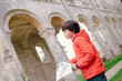 © Anna - Child visiting ruins of monastery Abbaye de Jumièges in Normandy, France. Boy holding museum plan  in his hands.