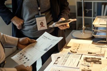Aufkleber - Hands of African American FBI agent looking through one of criminal profiles while standing by workplace in front of colleague