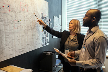 Aufkleber - Two FBI agents looking at map on board while mature female pointing at it and making suggestions about possible location of criminal