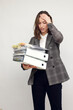 © Martin Villadsen - Frustrated and confused female worker and business woman holding a pile of paperwork while feeling aheadache. Looking stressed isolated on white background.