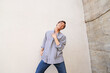 © Yuya Parker - Man dancing and smiling by concrete wall