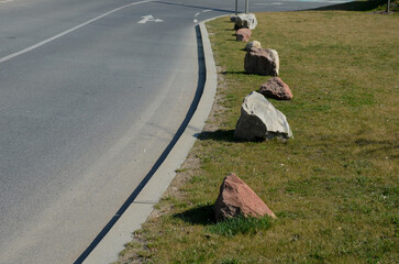 gray stones between the lanes as protection against parking. transport solutions in the parking lot by the country road and bike path. asphalt surfaces and lawn