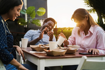 Multiracial people having fun eating at food truck restaurant outdoor - Focus on senior woman hand holding glass