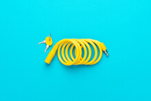 Yellow Bike Lock With Keys Over Turquoise Blue Background. Top Down Flat Lay Photo Of Bicycle Lock With Central Composition.