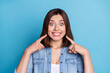 Photo of impressed funny woman wear jeans shirt pointing fingers teeth isolated blue color background