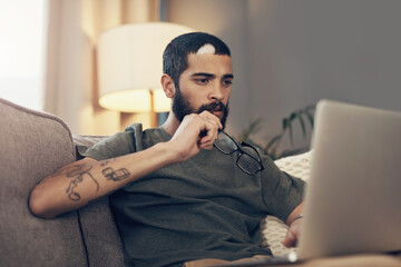 Sticker - Stay connected, stay aware of whats happening in the world. Shot of a young man using a laptop on the sofa at home.